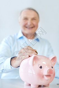 储蓄老商业人银行老人把硬币放进储蓄罐的特写高清图片