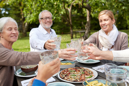 户外令人愉快的家庭,世代,假日人的快乐的家庭夏天的花园里吃晚饭碰杯背景