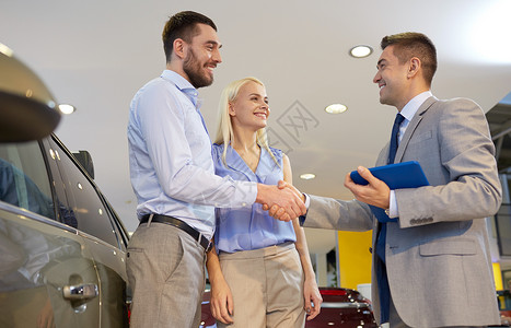 汽车业务,汽车销售,技术,手势人的幸福的夫妇与汽车经销商握手车展沙龙图片