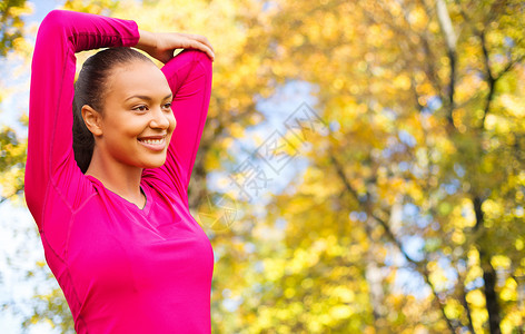 健身,运动,训练人的微笑的女人伸展秋天的公园背景图片