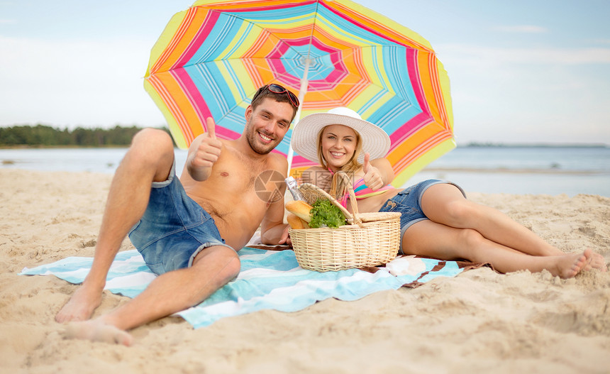暑假,假期快乐的人的快乐的夫妇与野餐篮阳伞大拇指海滩上图片