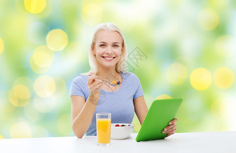 健康的饮食,饮食人的微笑的轻妇女与平板电脑吃早餐夏季绿色假期灯光背景图片