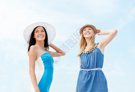 暑假假期女孩穿着连衣裙,戴着帽子海滩上女孩们穿着带帽子的裙子海滩上图片