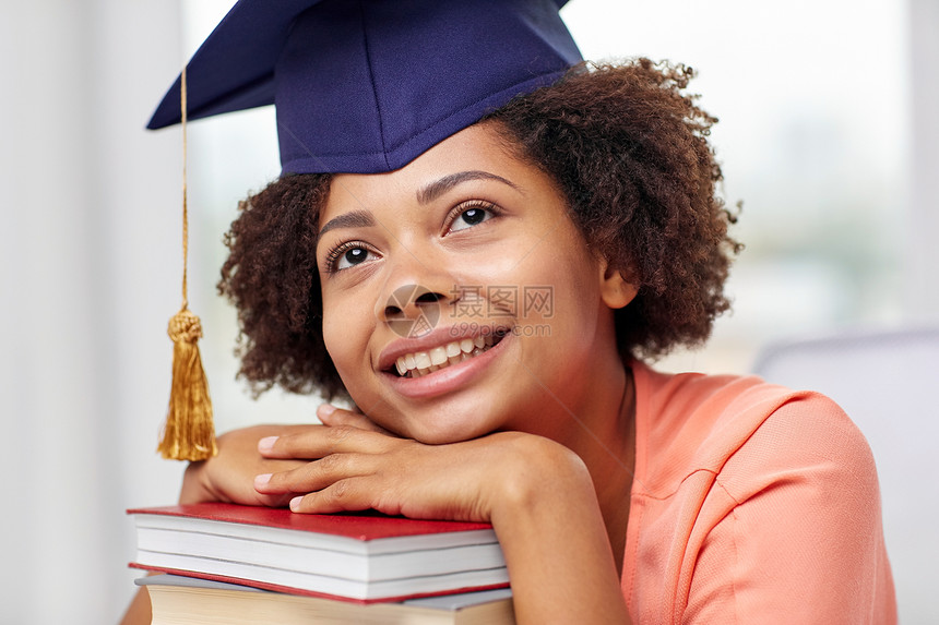教育,学校,知识,毕业人的快乐的微笑非裔美国学生女孩戴着学士帽,书坐桌子上,家里梦图片