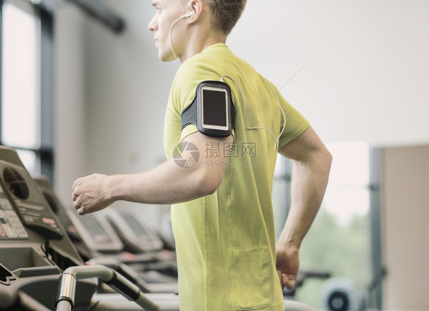 运动,健身,生活方式,技术人的智能手机耳机的人健身房的跑步机上锻炼图片