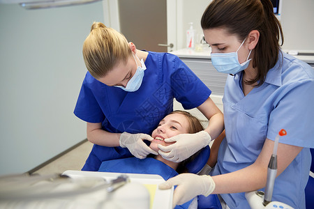 人,医学,口腔科牙齿护理快乐的女牙医与助理检查病人女孩牙合牙牙科诊所办公室背景图片