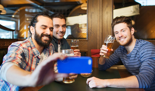 伙计们饮料人,休闲,友谊,技术单身派的快乐的男朋友与智能手机自拍喝啤酒酒吧酒吧背景