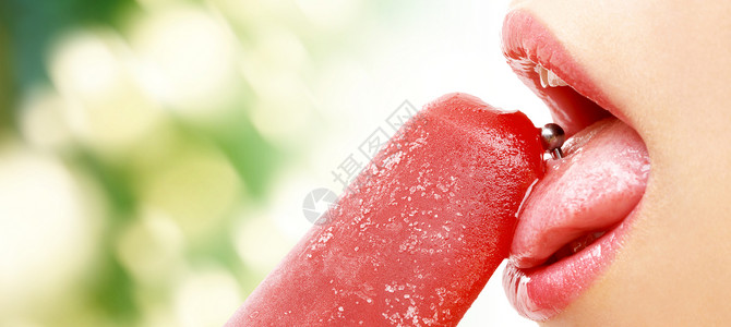 人,女人的嘴与穿孔舌头舔水果冰淇淋绿色的自然背景图片