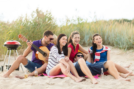 吉他架暑假,假期,音乐,快乐的人的群快乐的朋友海滩上野餐弹吉他背景