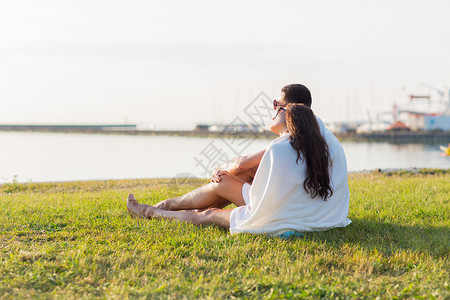 爱情,夏天,约会人的亲密的幸福夫妇坐海边的草地上图片