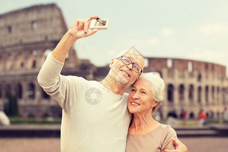 龄,旅游,技术人的老夫妇带着相机街头自拍的竞技场背景图片