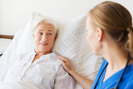 医生护士探视欢呼的老妇女躺医院病房图片