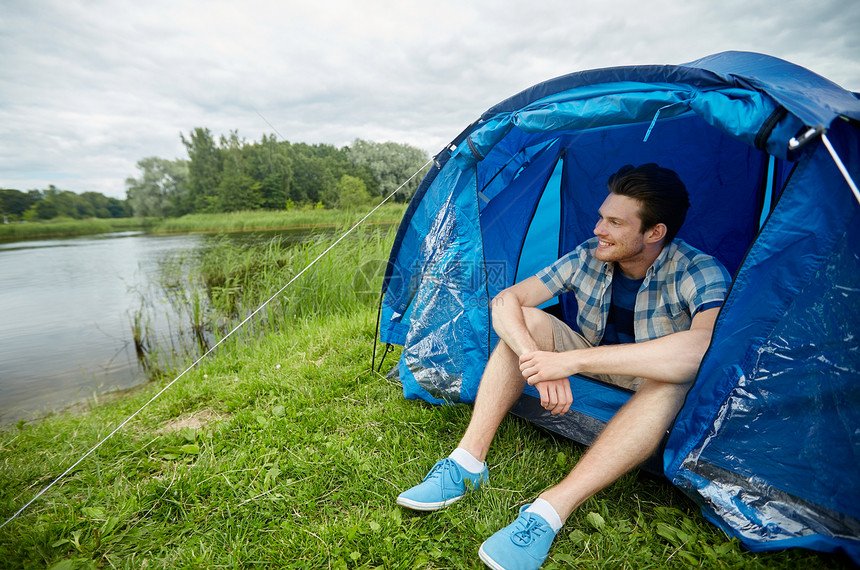旅行,旅游,徒步旅行,设备人的快乐的轻人坐帐篷里露营湖边河岸图片