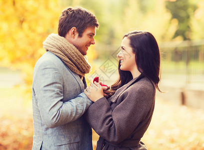 秋天公园里用红色的礼品盒特写微笑的夫妇图片