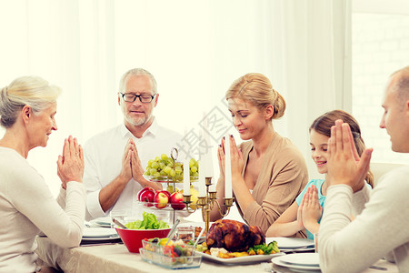家庭,假期,世代人的微笑的家庭家里吃饭祈祷图片