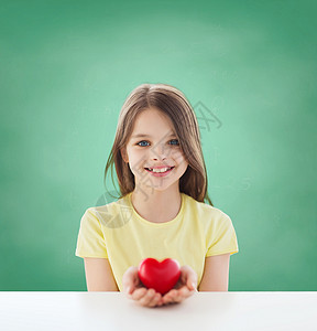 童,爱,慈善,教育人的微笑的小女孩坐着,抱着红色的心绿色的黑板背景上图片