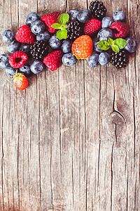 夏天的野生浆果破旧的木制背景上桌子上覆盆子草莓黑莓蓝莓图片