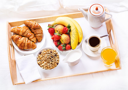 床上吃早餐托盘上咖啡牛角包谷类食品水果背景图片