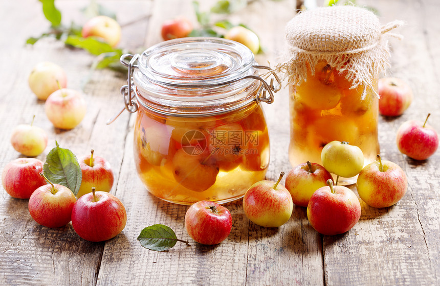 木制桌子上新鲜水果的苹果果酱罐子图片