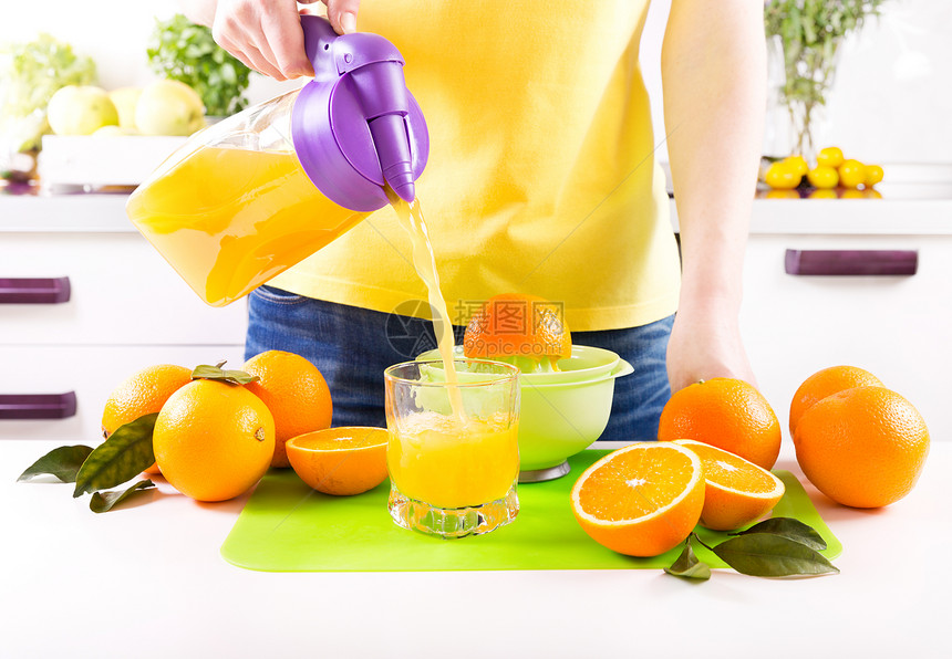 女人厨房把橙汁倒进璃里图片