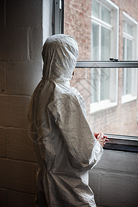 穿防化服的科学家站在窗前背景图片