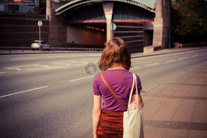 一个年轻的女人个阳光明媚的下午走条繁忙的路上图片