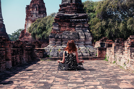 一个年轻的女人坐个古老的佛教寺庙的废墟中沉思图片