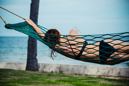 个轻的女人正海边的吊床上放松图片