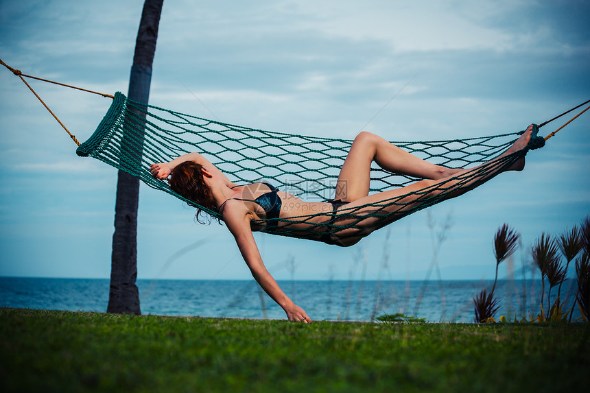 一个年轻的女人正海边的吊床上放松图片