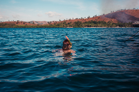 一个年轻的女人正热带岛屿附近浮潜,那里场火灾图片