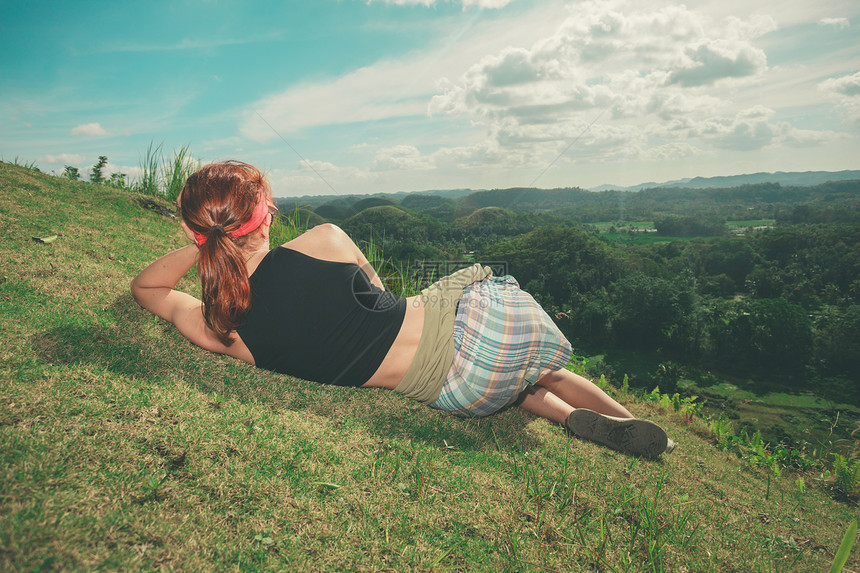一个年轻的女人躺山坡上,正欣赏菲律宾波霍尔的巧克力山的景色图片