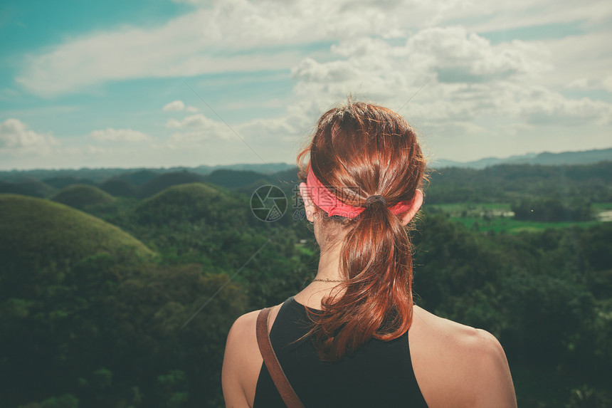 一个年轻的女子正欣赏菲律宾著名寻常的巧克力山的景色图片