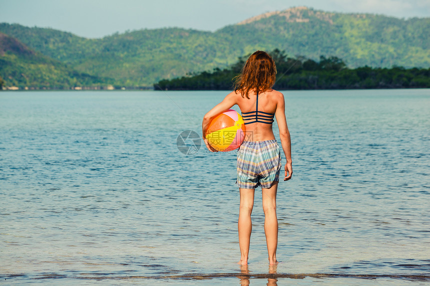 个轻的女人站热带海滩上着个沙滩球图片