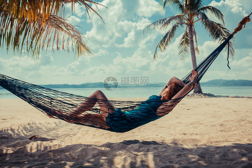 个轻的女人正热带海滩上的吊床上放松图片