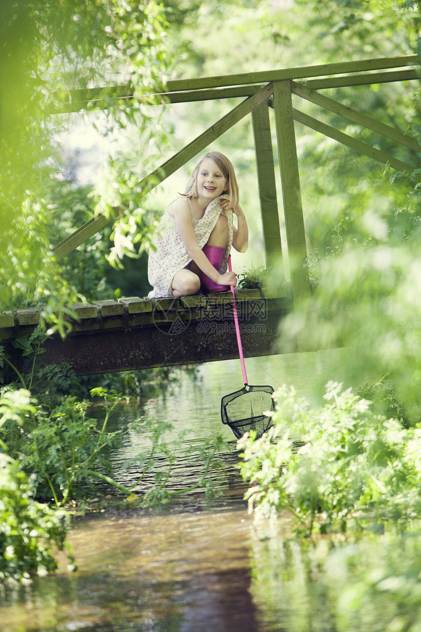 小女孩木桥上用网捕鱼图片