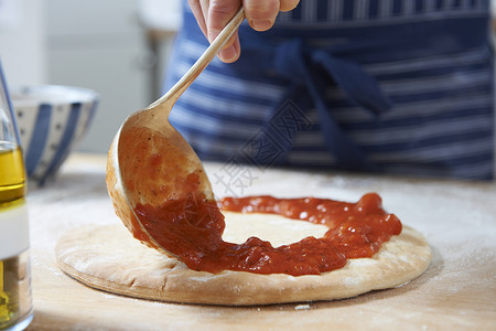 比萨饼基地添加番茄酱高清图片