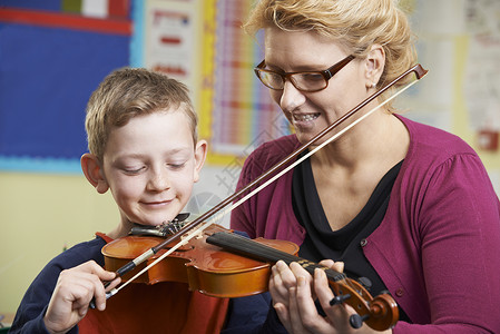 拉小提琴男孩老师音乐课上帮助学生拉小提琴背景