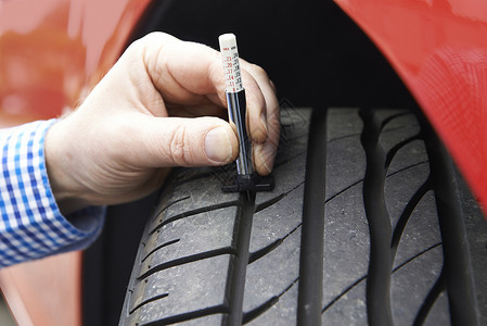 交规标志用量规检查汽车轮胎胎的人员特写背景