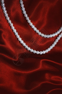 白色珍珠项链上的红色丝绸特写图片