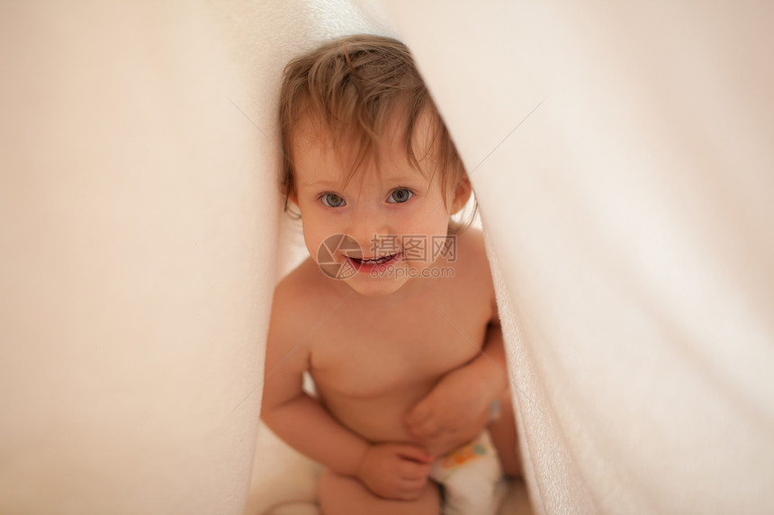 洗澡后蹒跚学步的孩子躲毯子下图片
