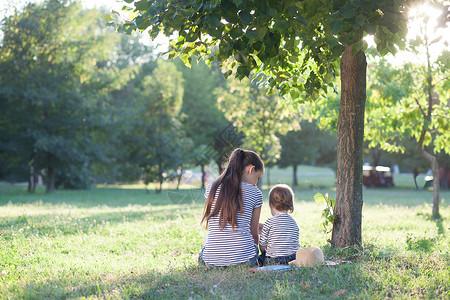 暑假里,妈妈蹒跚学步的孩子坐树下图片