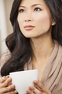 位美丽的轻的中国亚洲东方女,白色的杯子里喝茶喝咖啡图片