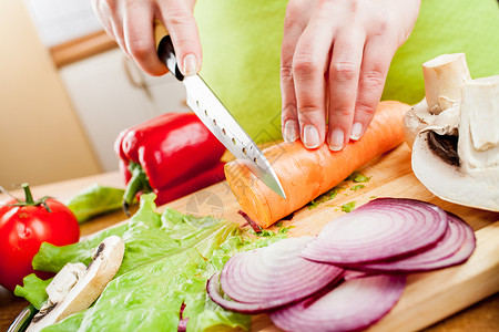 女人的手切胡萝卜,新鲜蔬菜后图片