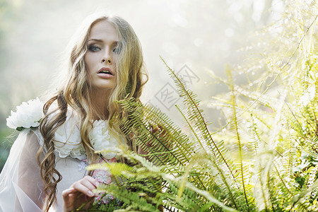 热带蕨菜旁边漂亮的金发女人图片