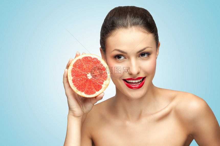 个美丽的女孩她的下巴下地抱着个红葡萄柚的创造肖像图片