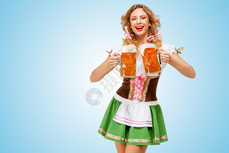 十月一活动轻感的啤酒节女人穿着件传统的巴伐利亚连衣裙,蓝色背景下为两个啤酒杯提供快乐的微笑背景