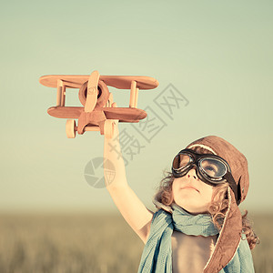 快乐的孩子蓝色的夏日天空背景下玩玩具飞机图片