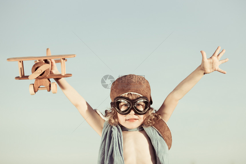 快乐的孩子蓝色的夏日天空背景下玩玩具飞机图片