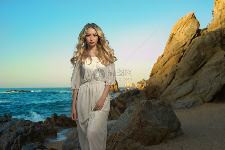 美丽的女士穿着白色连衣裙岩石海岸图片