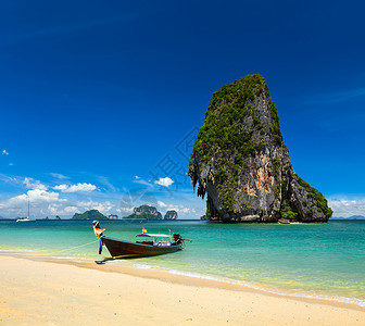 泰国热带度假背景热带海滩上的长尾船与石灰石岩石,泰国克拉比图片